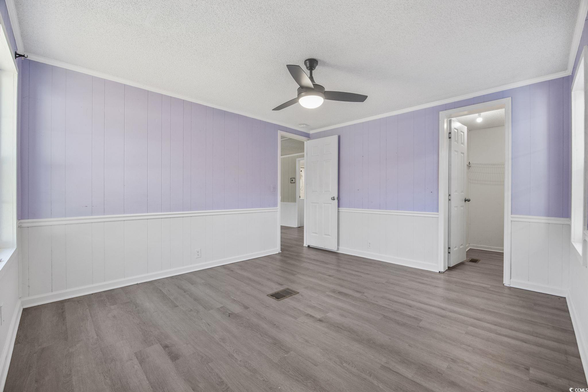 4221 Blake Road Myrtle Beach, SC 29588 - Photo 24 of 36 Unfurnished bedroom with crown molding, wood finished floors, a textured ceiling, a walk in closet, and ceiling fan