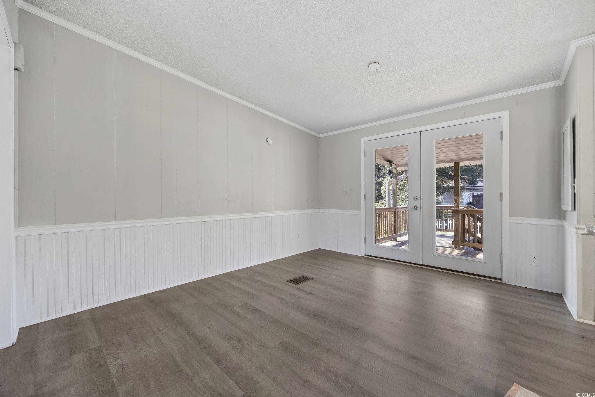 4221 Blake Road Myrtle Beach, SC 29588 - Photo 5 of 36 Unfurnished room with crown molding, wood finished floors, french doors, wainscoting, and a textured ceiling