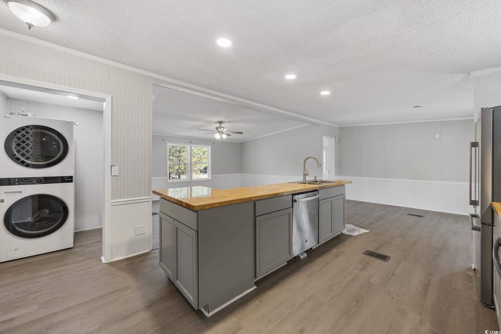 4221 Blake Road Myrtle Beach, SC 29588 - Photo 7 of 36 Kitchen with butcher block counters, crown molding, an island with sink, gray cabinetry, and light wood-style flooring