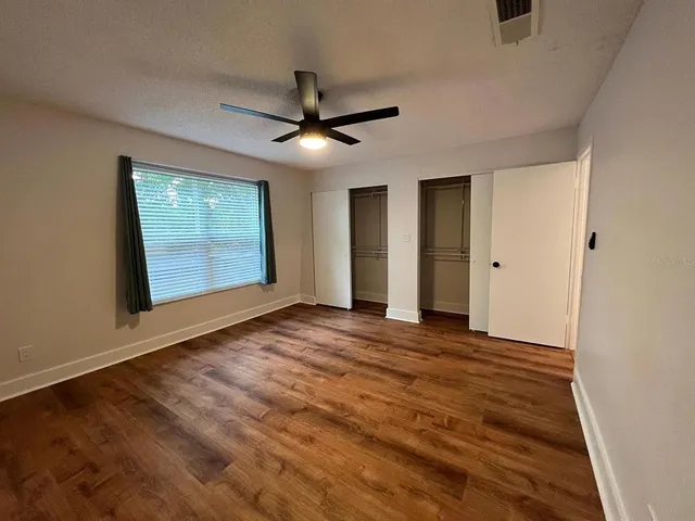 a view of an empty room with a window and a ceiling fan