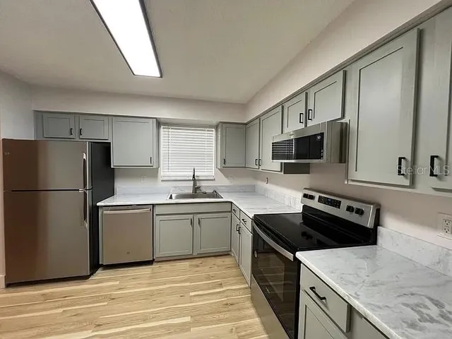 a kitchen with stainless steel appliances granite countertop a sink stove and refrigerator