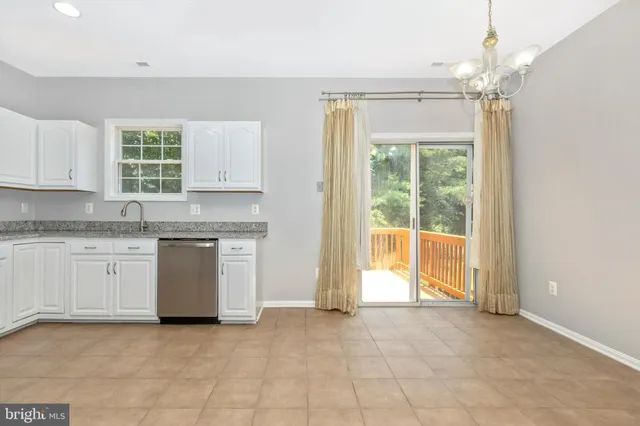 a open kitchen with granite countertop a stove a sink dishwasher and white cabinets with wooden floor