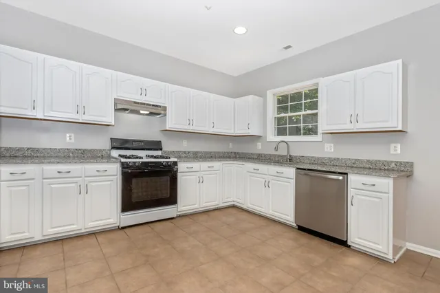 a kitchen with granite countertop white cabinets and stainless steel appliances