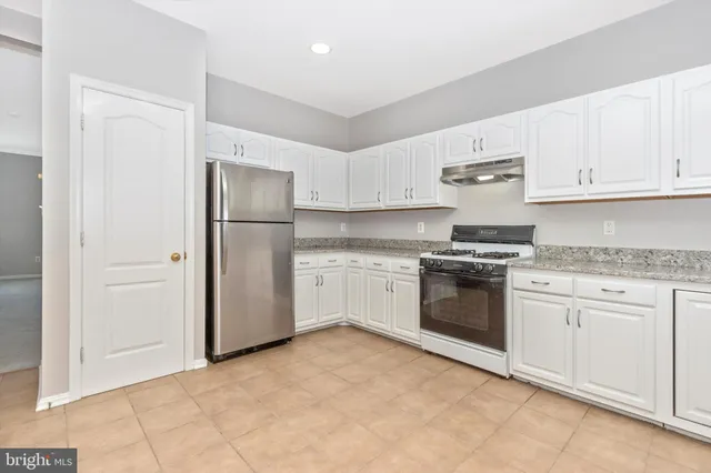 a kitchen with granite countertop white cabinets and white stainless steel appliances