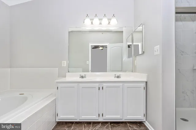 a bathroom with a double vanity sink mirror and bathtub