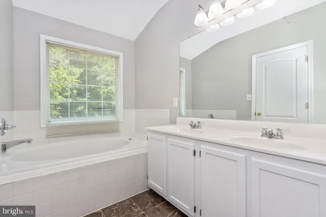 a bathroom with a tub a sink and mirror