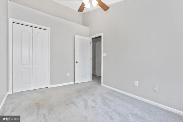 an empty room with a fan & a window