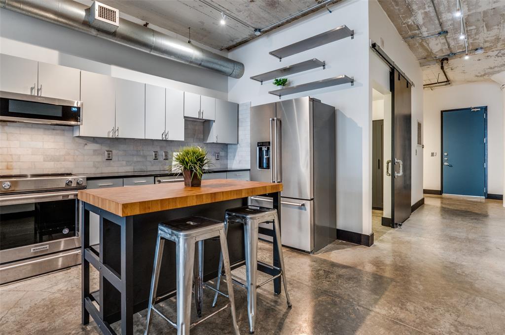 1122 Jackson Street, Unit 917 Dallas, TX 75202 - Photo 6 of 19 a kitchen with stainless steel appliances granite countertop a table chairs refrigerator and sink