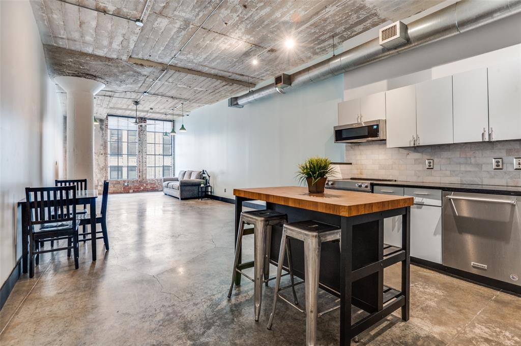 1122 Jackson Street, Unit 917 Dallas, TX 75202 - Photo 9 of 19 a kitchen with stainless steel appliances granite countertop a table chairs sink and cabinets