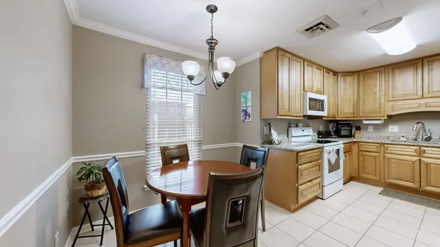 a kitchen with stainless steel appliances granite countertop a dining table chairs and a refrigerator