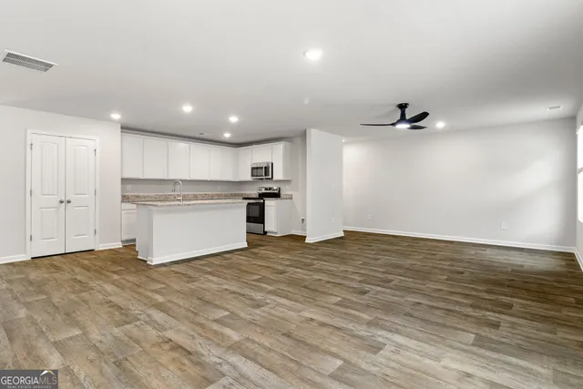 an empty room with windows and ceiling fan