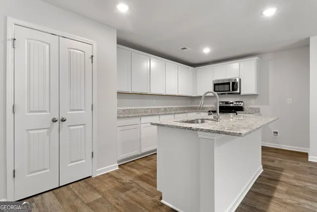 a kitchen with granite countertop white cabinets and stainless steel appliances