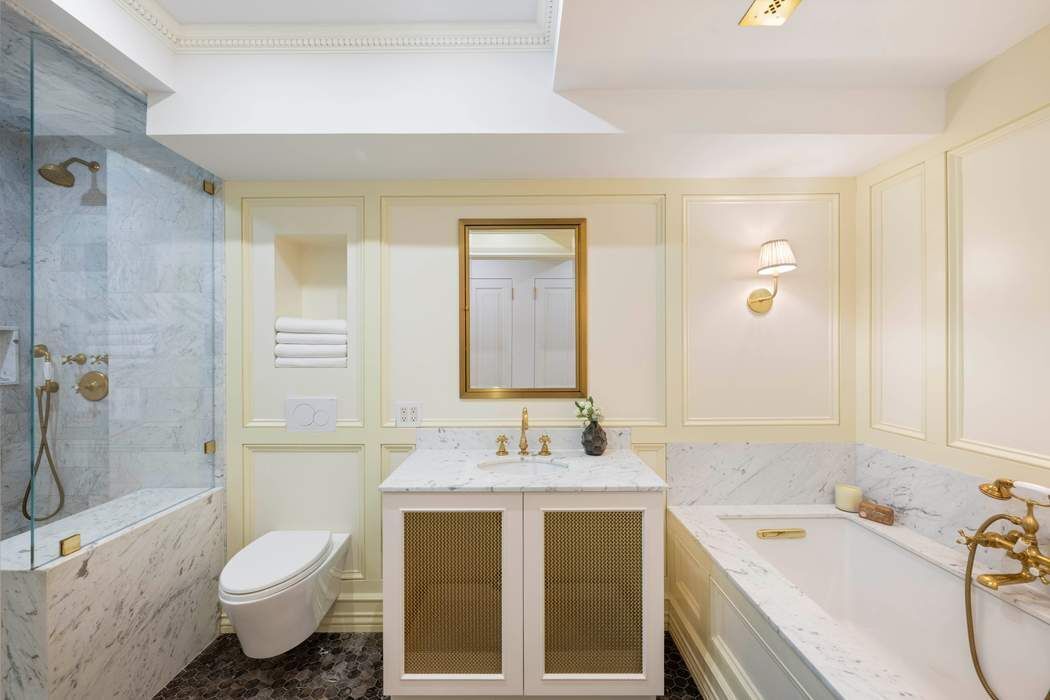 47 East 87th Street, Unit 7A Manhattan, NY 10128 - Photo 8 of 14 a bathroom with a tub sink toilet and a mirror