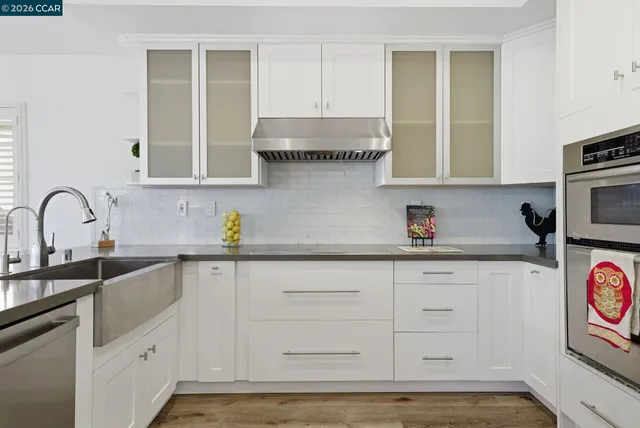 a kitchen with stainless steel appliances granite countertop a refrigerator sink and white cabinets