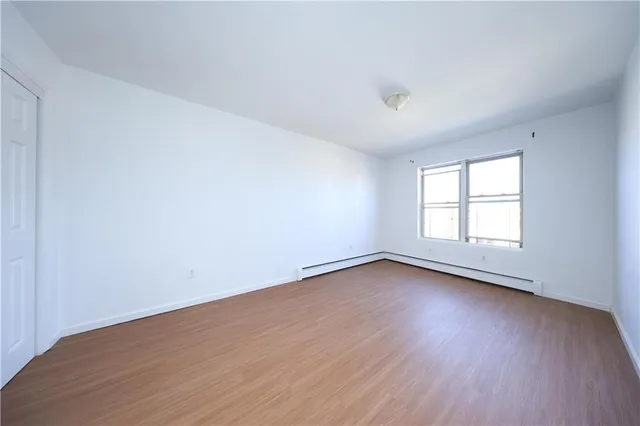 a view of an empty room with wooden floor and window