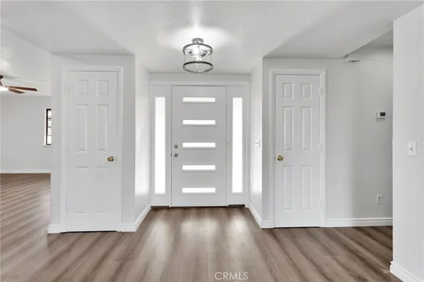 a view of an empty room with wooden floor and window