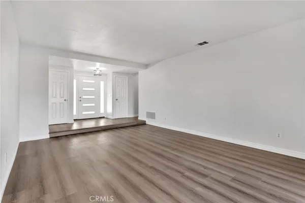 a view of an empty room with wooden floor fireplace and a window
