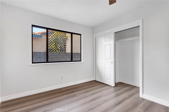 an empty room with wooden floor fan and windows