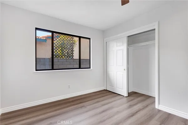 an empty room with wooden floor fan and windows