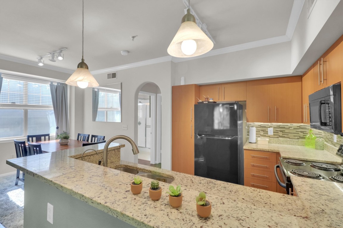 11203 Ranch Road 2222, Unit 2305 Austin, TX 78730 - Photo 5 of 36 a kitchen with kitchen island granite countertop a sink stainless steel appliances and cabinets