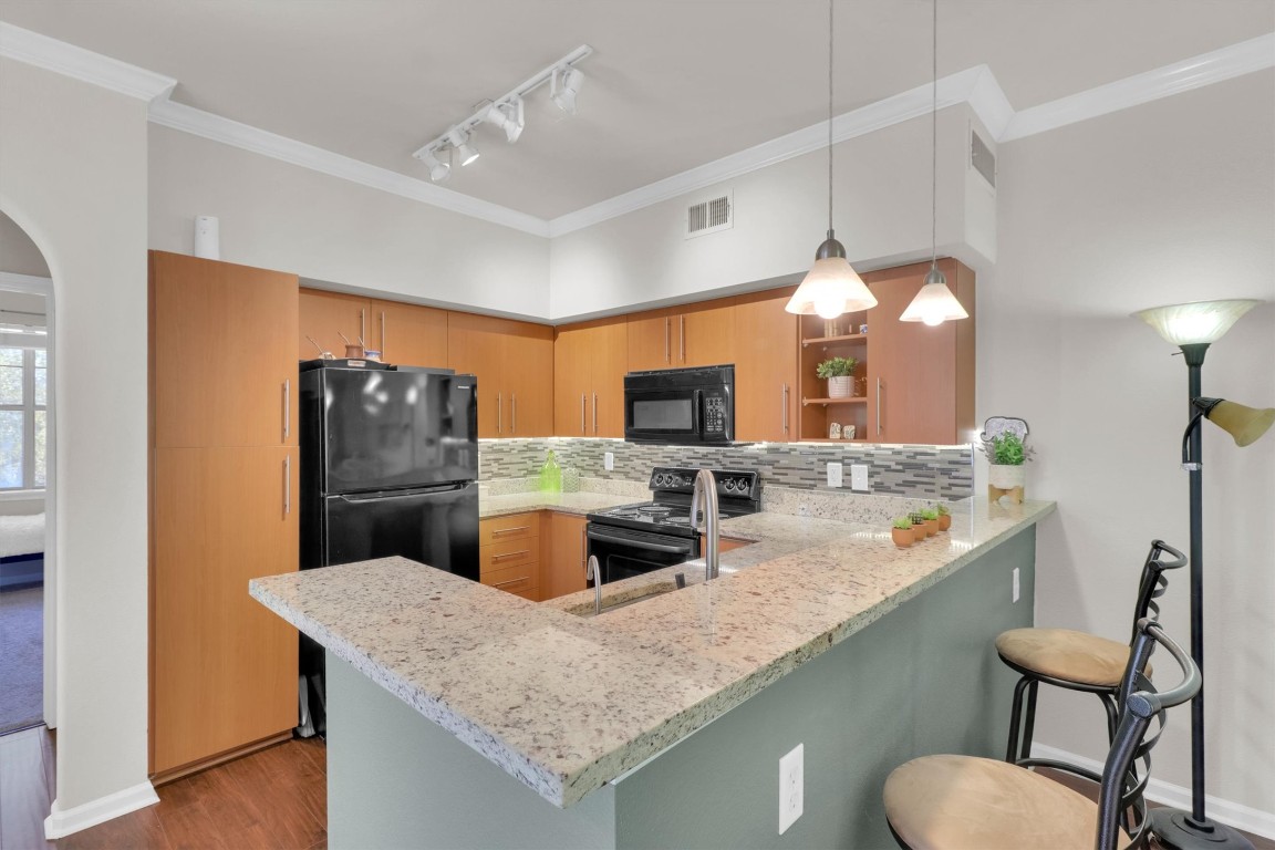 11203 Ranch Road 2222, Unit 2305 Austin, TX 78730 - Photo 6 of 36 a kitchen with stainless steel appliances granite countertop a kitchen island a stove a sink a refrigerator and chairs