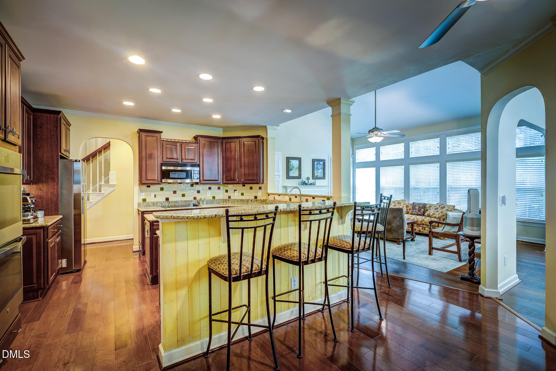 12212 Ashton Woods Lane Raleigh, NC 27614 - Photo 13 of 50 a kitchen with stainless steel appliances kitchen island granite countertop a refrigerator a stove a dining table and chairs with wooden floor