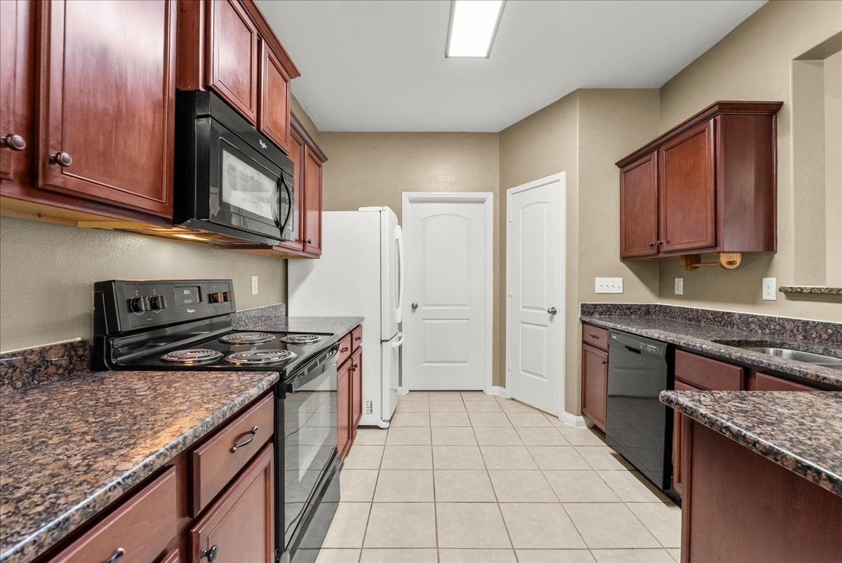 322 Shoshone Ridge Drive La Marque, TX 77568 - Photo 12 of 34 a kitchen with stainless steel appliances granite countertop a stove top oven a sink dishwasher and a refrigerator with wooden cabinets