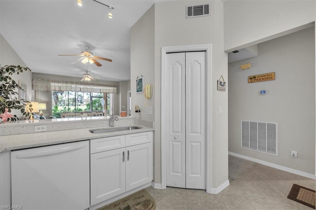 8075 Tiger Cove, Unit 1706 Naples, FL 34113 - Photo 14 of 50 Kitchen featuring white dishwasher, ceiling fan, white cabinets, light tile patterned floors, and light stone counters