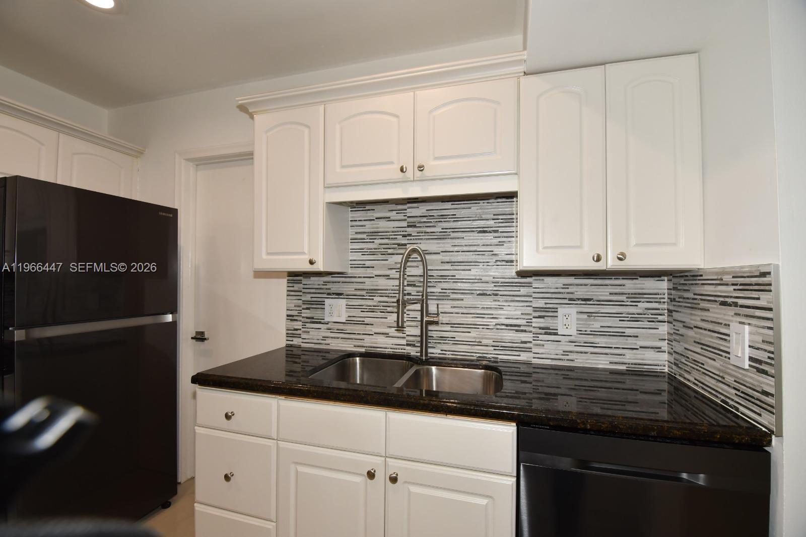 7200 Northwest 2nd Avenue, Unit 410 Boca Raton, FL 33487 - Photo 4 of 20 a kitchen with granite countertop white cabinets and black appliances