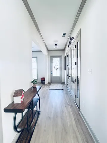 a view of a hallway with wooden floor and furniture