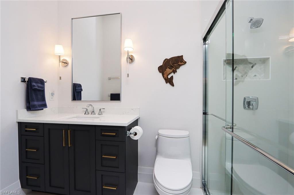 6665 Mill Run Road Naples, FL 34109 - Photo 20 of 30 a bathroom with a granite countertop sink a toilet and shower