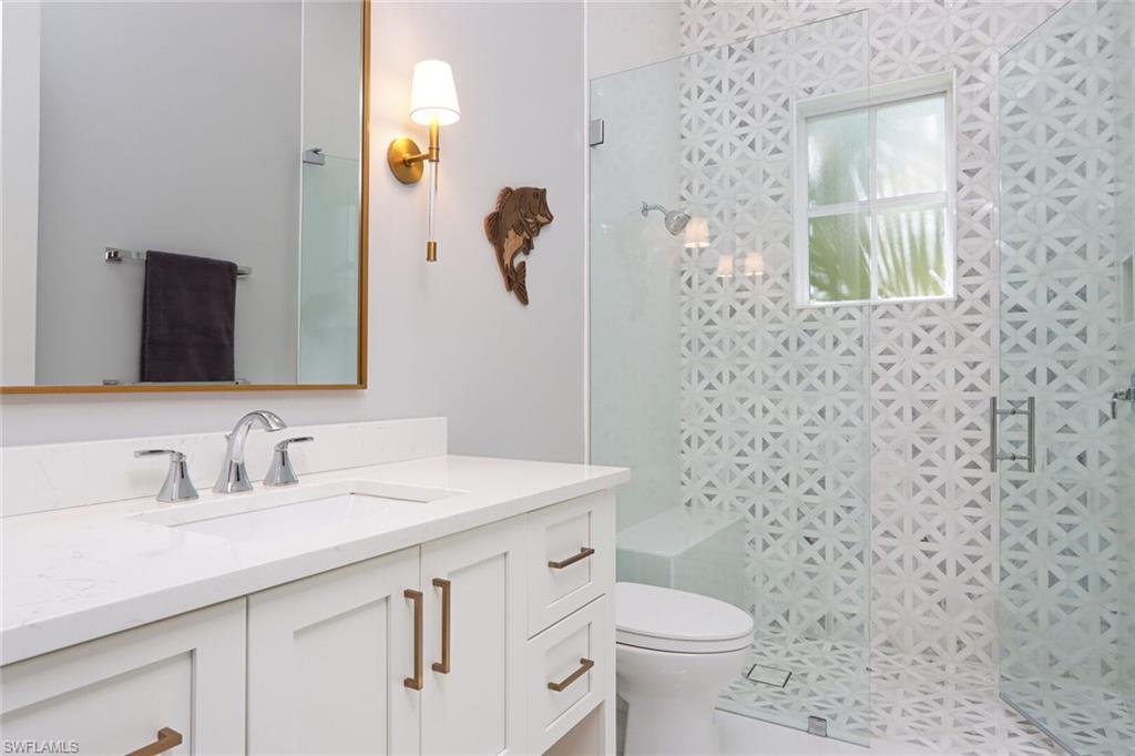 6665 Mill Run Road Naples, FL 34109 - Photo 21 of 30 a bathroom with a granite countertop toilet sink and mirror