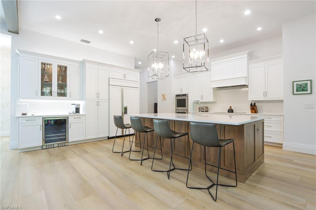 6665 Mill Run Road Naples, FL 34109 - Photo 5 of 30 a kitchen with stainless steel appliances a dining table chairs stove and cabinets