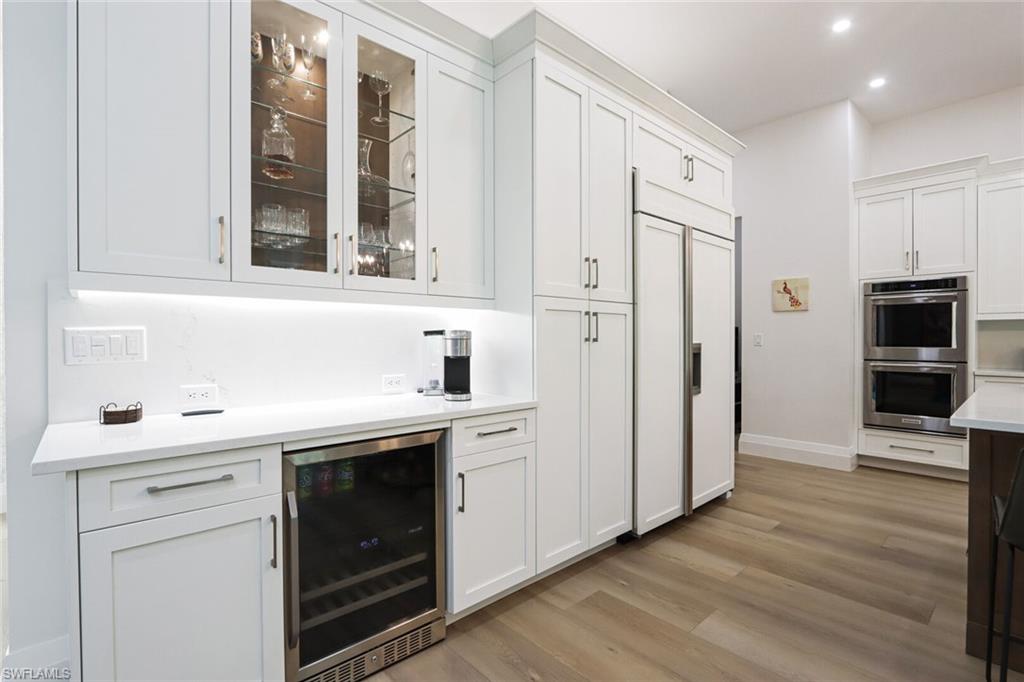 6665 Mill Run Road Naples, FL 34109 - Photo 9 of 30 a kitchen with stainless steel appliances white cabinets and wooden floors