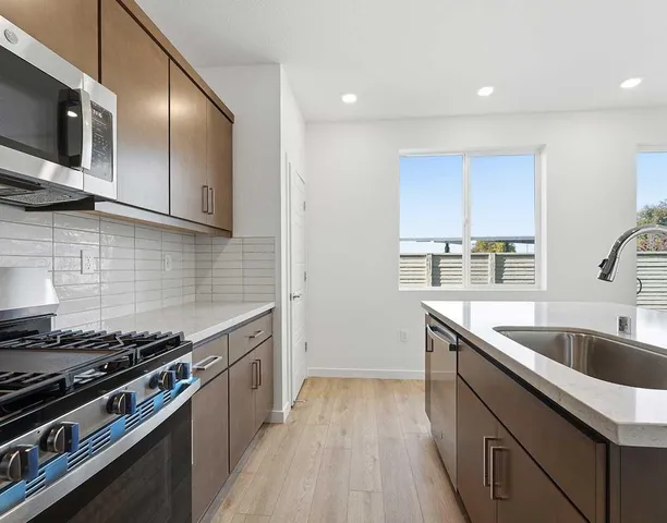 a kitchen with stainless steel appliances granite countertop a sink stove and cabinets