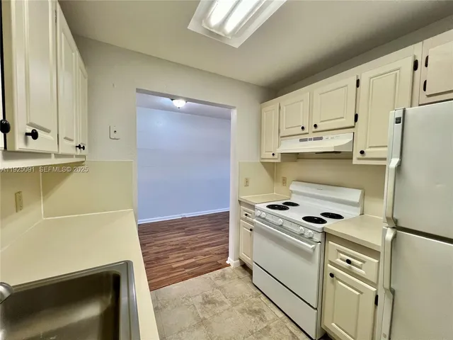 a kitchen with white cabinets and white appliances