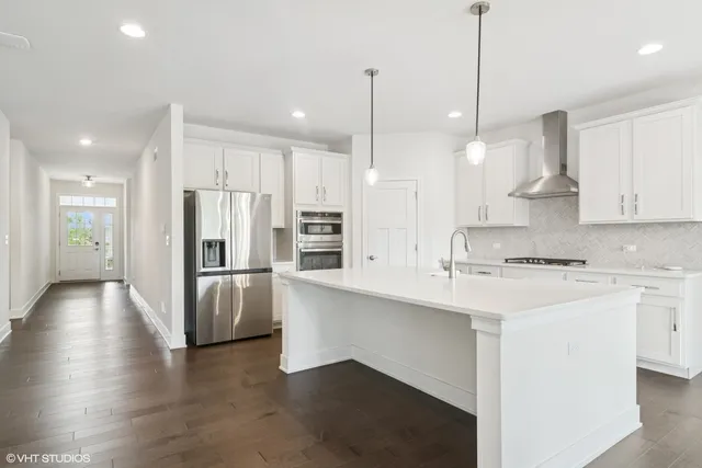 a kitchen with stainless steel appliances kitchen island a refrigerator a sink a stove and white cabinets