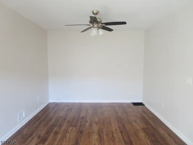 a view of a room with wooden floor and a ceiling fan