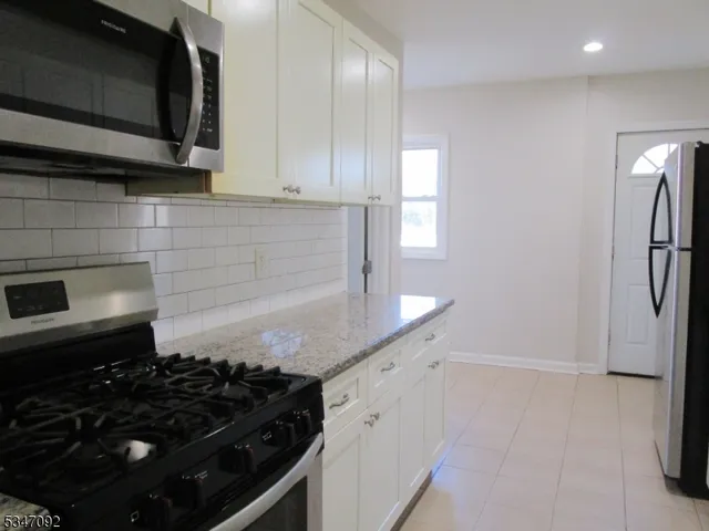 a kitchen with granite countertop a stove and a microwave