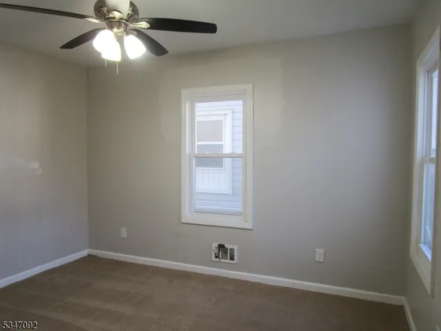 an empty room with a window and a fan