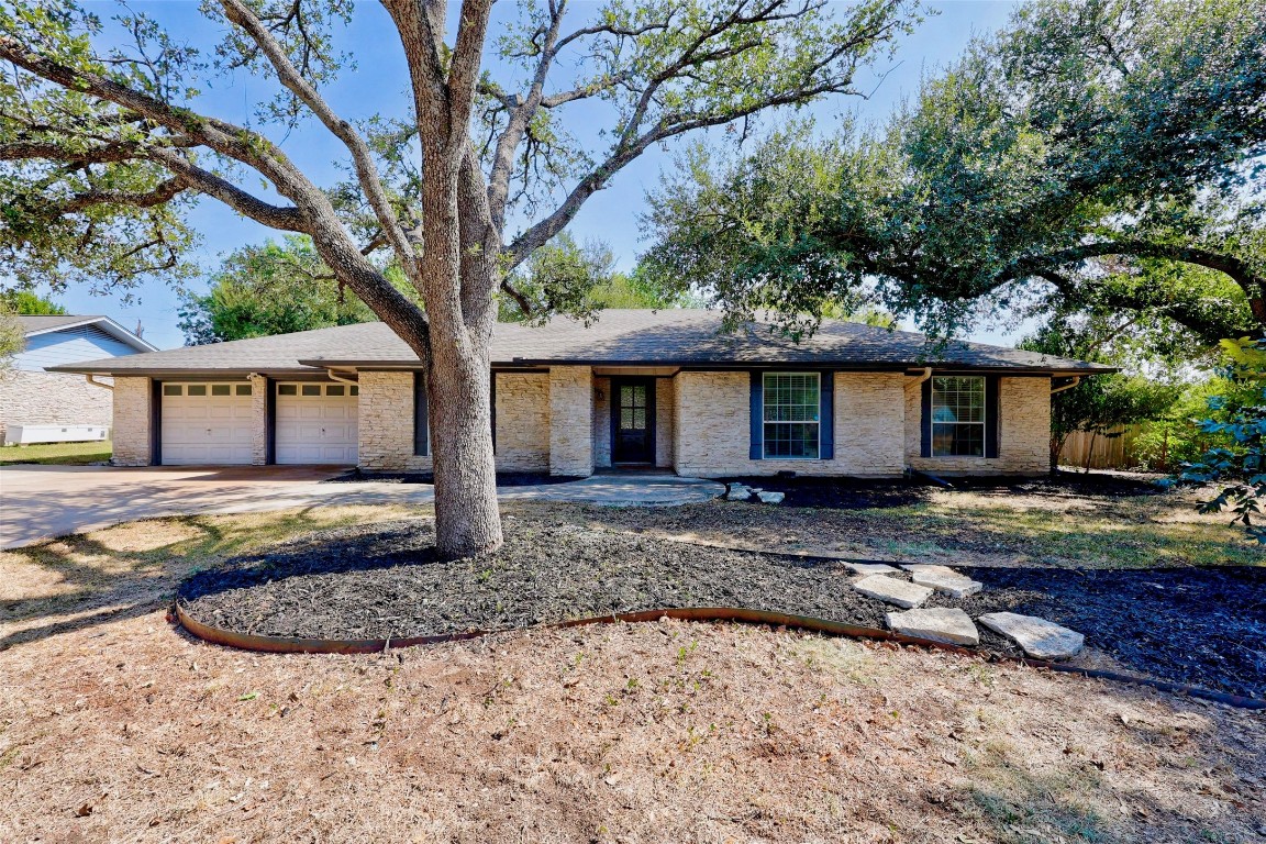 a view of a house with a yard and large tree