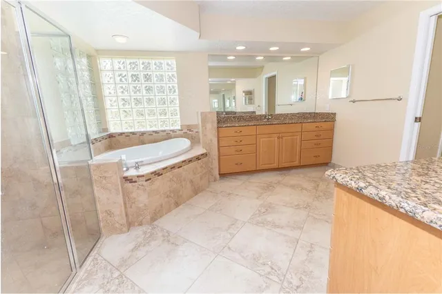 a large bathroom with a granite countertop tub sink and mirror