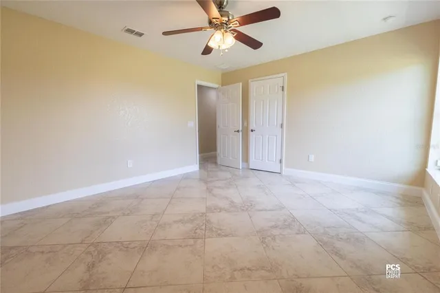 a view of an empty room and chandelier fan