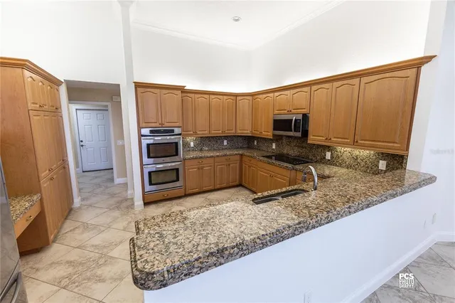 a kitchen with granite countertop a stove a sink and a microwave