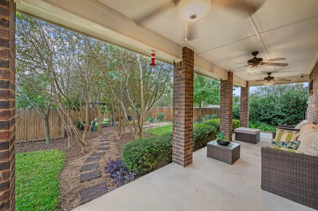 a view of a patio with couches plants and large trees