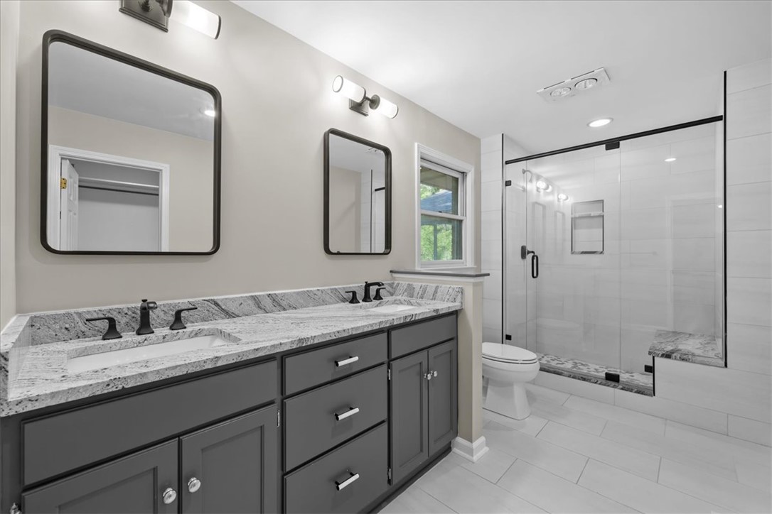 103 Satula Lane Clemson, SC 29631 - Photo 32 of 50 This primary bathroom boasts a dual-sink vanity with elegant granite countertops and a spacious glass-enclosed shower.