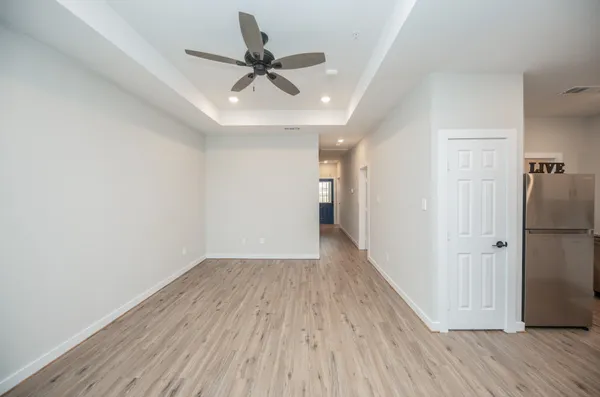 a view of a hallway with wooden floor and a chandelier fan