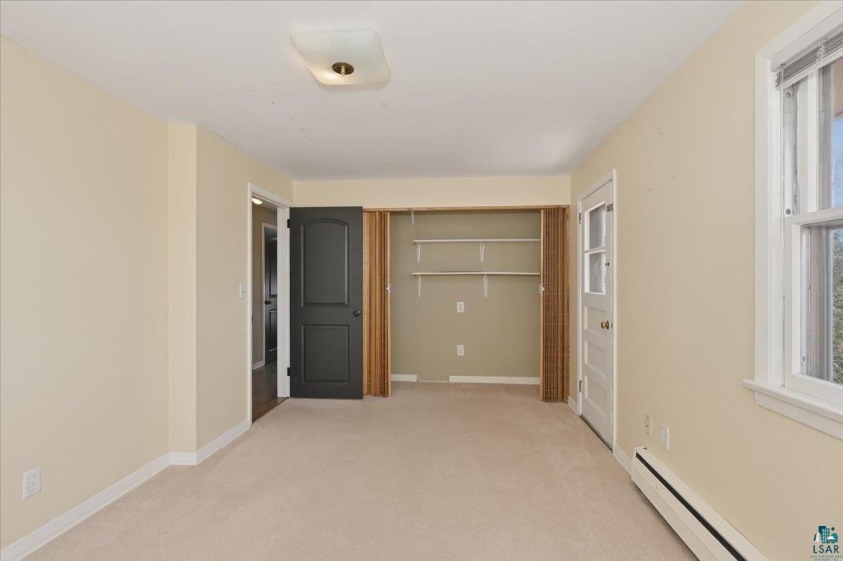 1918 West Kent Road Duluth, MN 55812 - Photo 25 of 42 Neutral-toned room with plush carpeting, a built-in closet featuring shelving, a window with white trim, and a ceiling-mounted light fixture