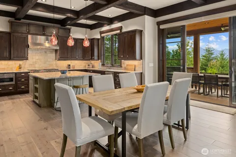 a dining room with stainless steel appliances granite countertop a table chairs and a wooden floor