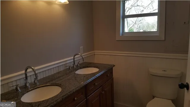 a bathroom with a granite countertop sink a toilet and a mirror